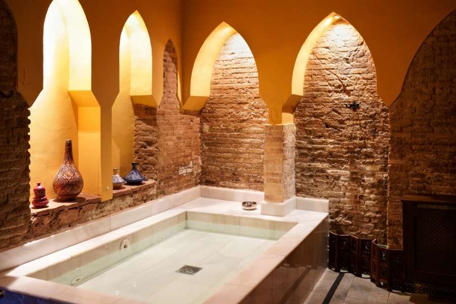 Un bassin d'eau chaude au cœur d'un établissement traditionnel inspiré du rituel de hammam marocain.